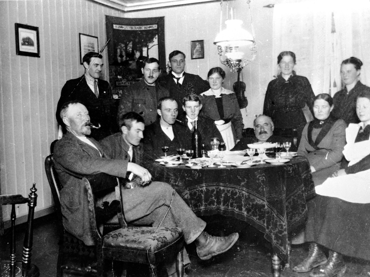 Anno Domkirkeodden, Interiør stue på Ulven, Ring. Fra venstre er ukjent, Even Mengshoel, ukjent, Agnes Mengshoel, ukjent, Jenny Lier. Sittende er A.G. Kinde, Nils Haugen, Mons Lier, Ole Lier, Andreas Lier, Mathea Lier, Petra Mengshoel.