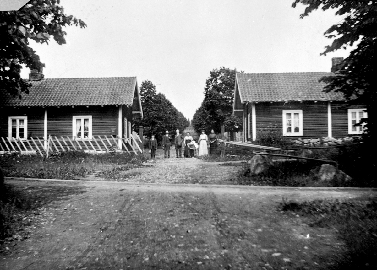 Anno Domkirkeodden, Eksteriør, portstuene på Hoel gård, Nes, Hedmark. Personene er ikke kjent. Bygningene ble bygd før 1875. De ble revet i 1950-åra.