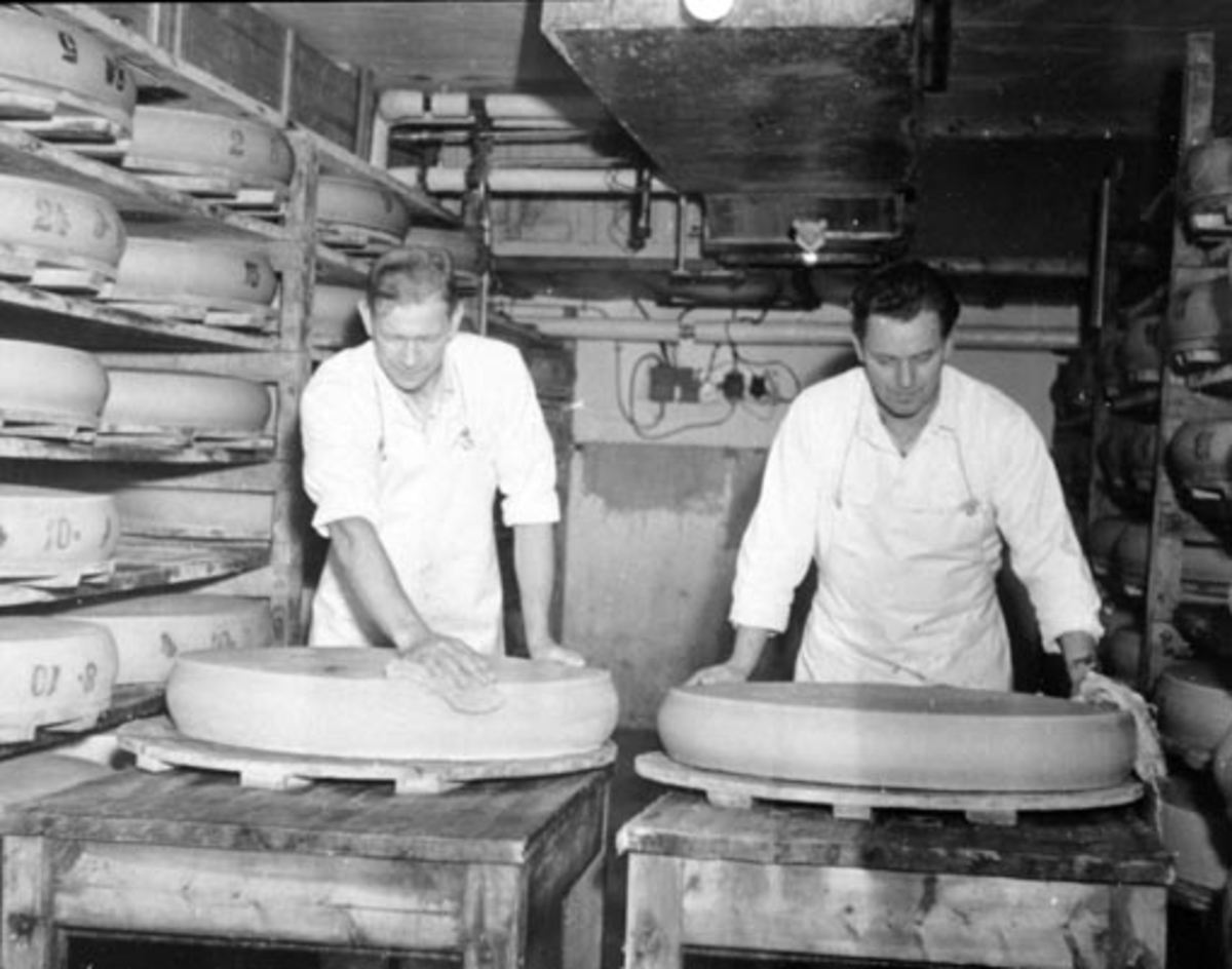 Anno Domkirkeodden, Interiør fra Nes Meieri, Nes, Hedmark. Lager for modnind av ost. To menn vasker og snur osten. Arve Edvardsen (1919-1988) til venstre.