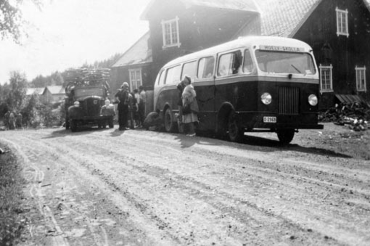 Anno Domkirkeodden, Buss, en Studebaker 1935-36, D-2968. Foran Mølla i Næroset, Ringsaker. Rute fra Moelv til Skolla seter. Passasjerer. Volvo lastebil, D-2492. Karosseriet til bussen ble bygd ved Brumunddal mekaniske verksted. Ødelagt i tysk krigstjeneste og gjennoppbygd av Moelv Elektro & Auto og tatt i bruke av rut…