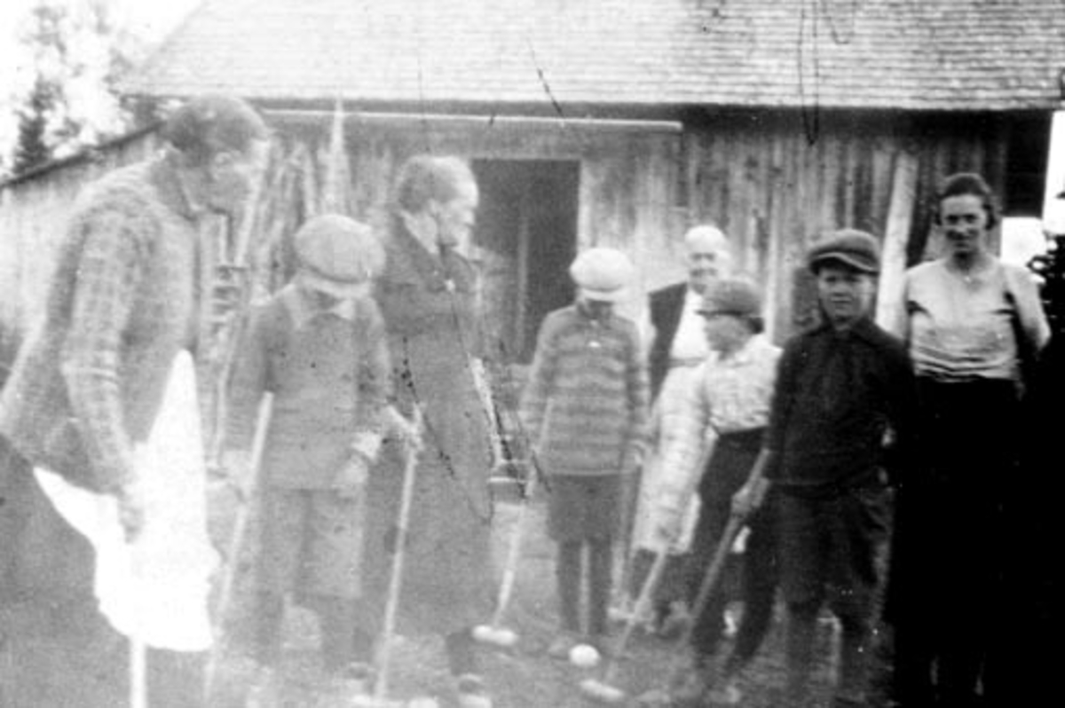 Anno Domkirkeodden, Voksne og barn spiller krokket. I bakgrunnen er låven i skredder-Rykop under Skapal, Rudshøgda, Ringsaker. Præstvegen.