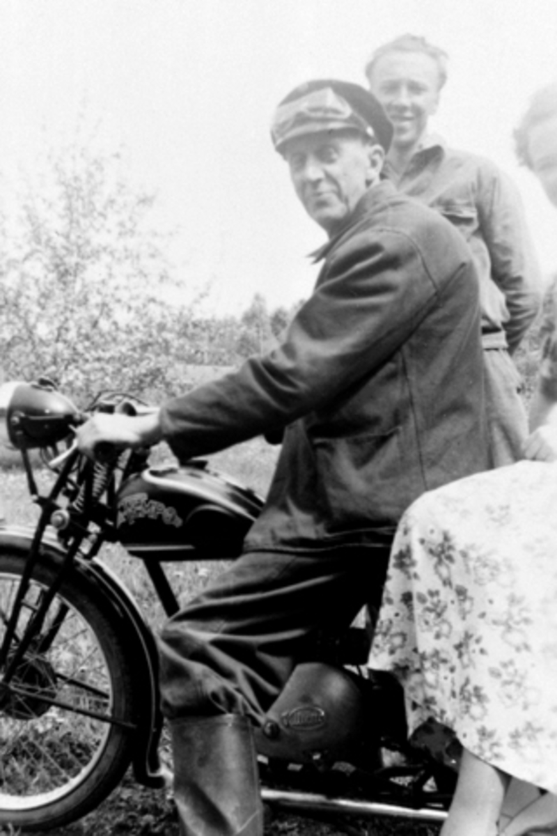 Anno Domkirkeodden, Landpostbud ("Pær Post") Peder Kristian Nilsen Furulund (1892-1972) på motorsykkel D-1775. I bakgrunnen er Even Lie (1928-1990), Smedstuen nedre, Nes, Hedmark.