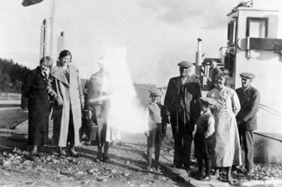 Anno Domkirkeodden, Mjøsfergen ved brygga på Smedstuen nedre, Nes, Hedmark. Fra venstre er Mary Lie (1898-1981), ukjent, ukjent, Even Lie Jr (1928-1990), Even Arnt Andreassen Lie (1865-1938), Arne Wedrik Lie f.1938, Signe Lie (1902-1993), Arne Lie (1894-1989).