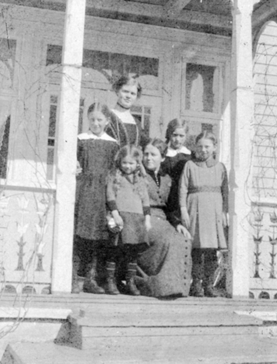 Anno Domkirkeodden, Flatby i Nygata, Brumunddal. På verandaen i Flateby 1912. Foran f. v. Halgerd, Oline og Lily Mælum. Bak f. v. ukjent, Laura Grebstad (senere poståpner) Paula Mælum. "Flatby-Mælum".