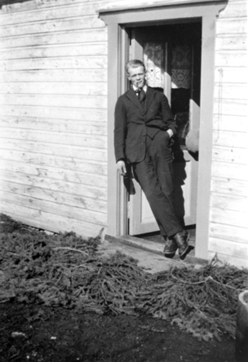 Anno Domkirkeodden, Rolf Lindby (1906-1976) i døråpninga i Skogly, Helgøya. 1928. Granbar foran døra.