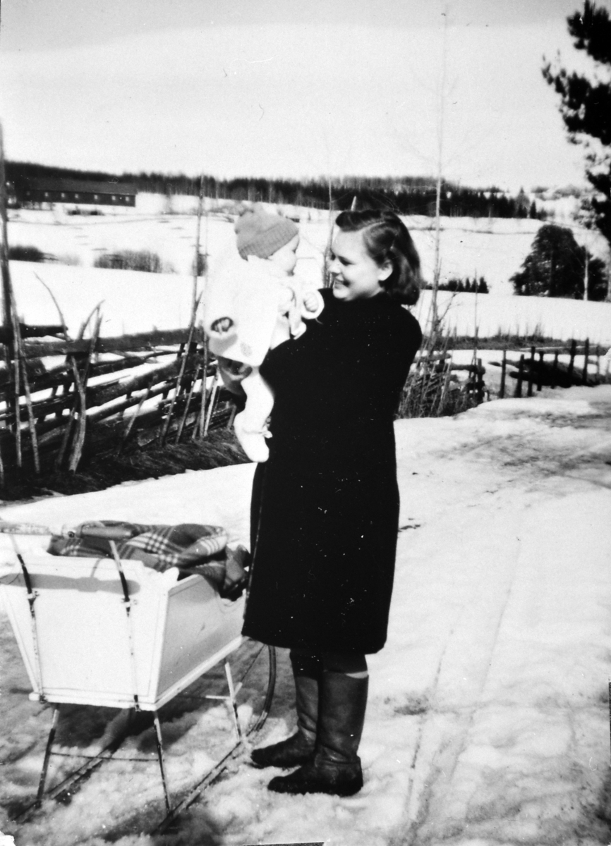 Anno Domkirkeodden, En vårdag langs Præstvægen. Tokstad gård i bakgrunnen. Tokstadfurua i kanten til høyre. Ukjente dame med barn og sluffe. Skigard.