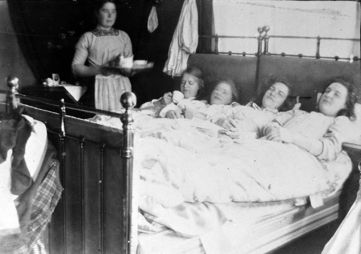 Anno Domkirkeodden, Simenstad gard i Veldre. Bnr. 138-1. Kaffeservering på senga. Interiør soverom. Fra venstre Julie, Kristine (usikker), Grethe og Dorothea Simenstad,