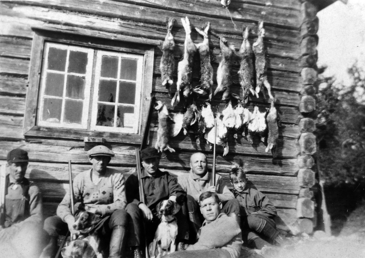 Anno Domkirkeodden, Jaktlag foran tømmerhus. Jaktutbytte, hare og fugl på veggen. Foran er Aksel Johansen, til venstre er Ole O. Houmb.
