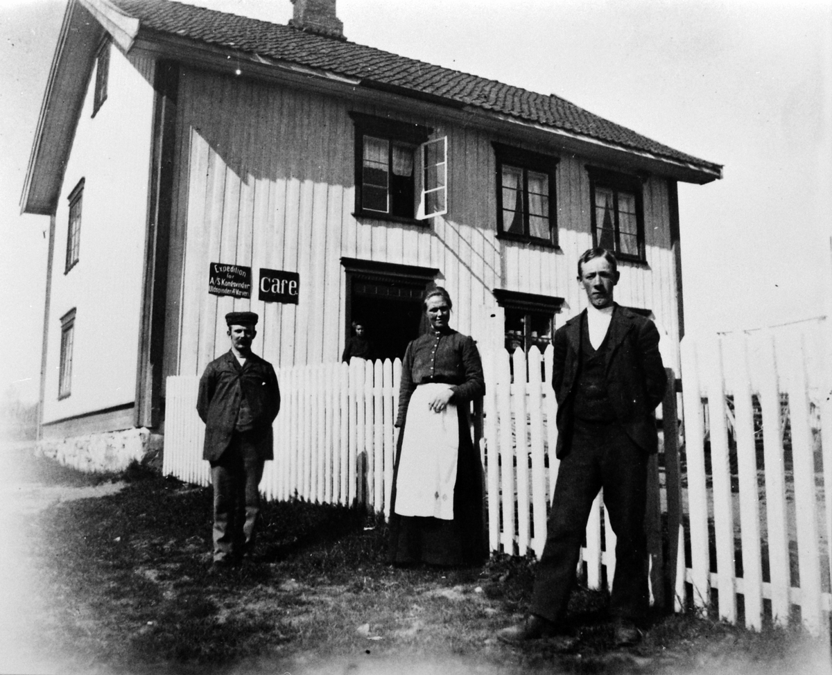 Anno Domkirkeodden, Føderådsbygningen på Jessnes nedre der Julius Røset begynte landhandel like etter hundreårskiftet. På bildet er Julius og Karen Røset, handelsbetjent Kristian Schjerpen. På skiltene "Expedition for A/S Kongsvinger Uldspinderi&Væveri" og "Cafe".
