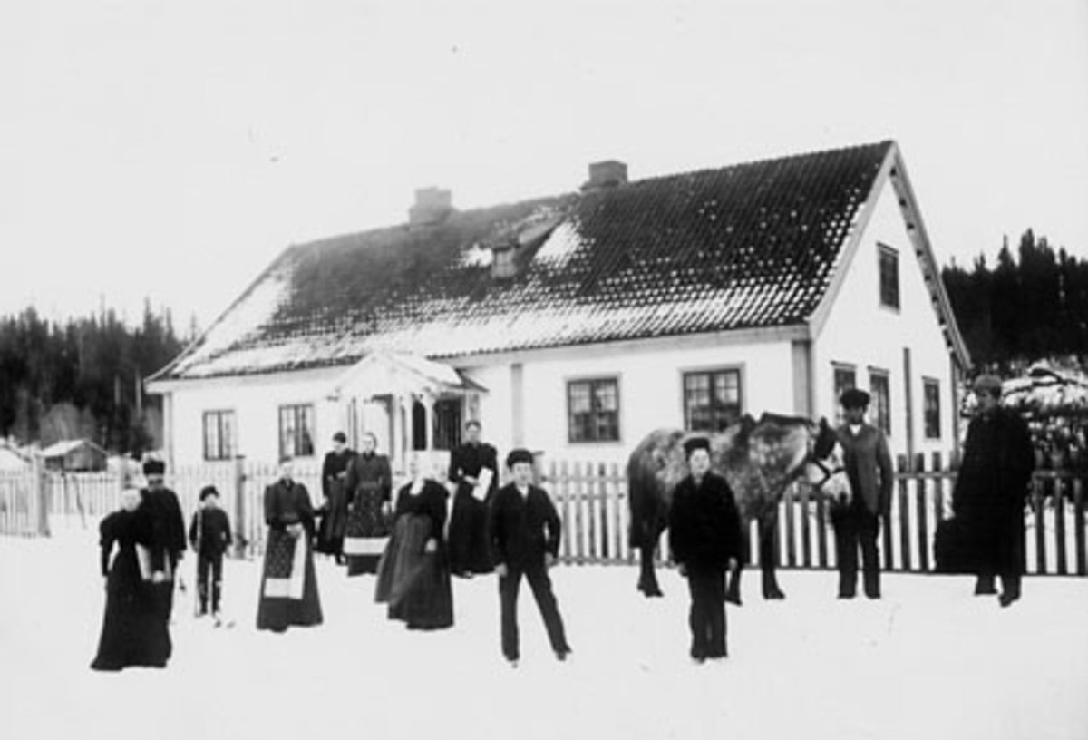 Anno Domkirkeodden, EKSTERIØR: HOVEDBYGNINGEN, BAKSTAD FØR RESTAURERING 1917, GRUPPE: 12, FRA VENSTRE: LINA BAKSTAD, ANDERS BAKSTAD, UKJENT, OLAVA BAKSTAD, UKJENT, SYVERINE BAKSTAD, OLINE BAKSTAD, MARTE BAKSTAD, PER O ENGEN, LARS MANGERUD, EVEN BAKSTAD, MARTHINUS HARILDSTAD