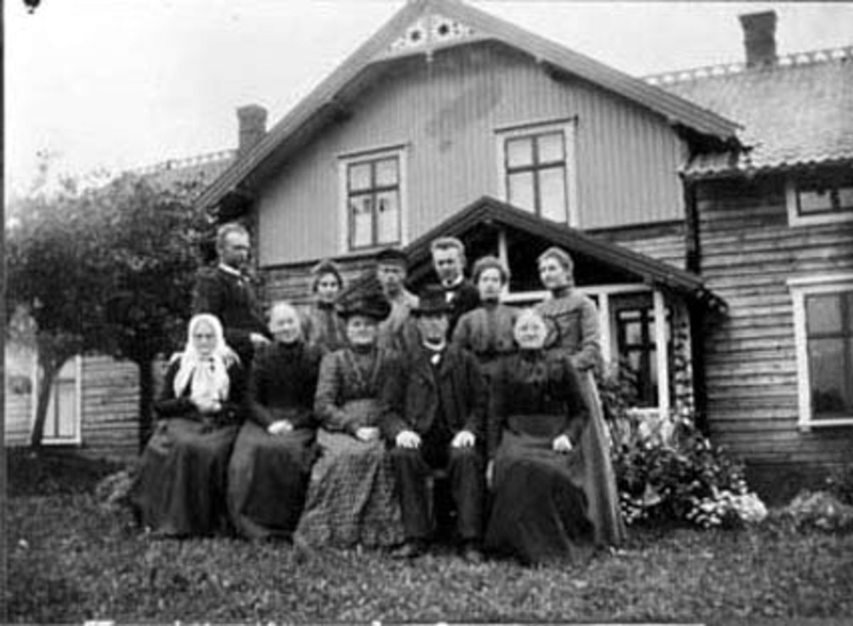 Anno Domkirkeodden, EKSTERIØR: FØRRÅDSBYGNING GAUSTAD GÅRD, GARDSBRUK, GRUPPE: 11 FAMILIEN GAUSTAD, I MIDTEN: FRODE GAUSTAD, OCTAVIA GAUSTAD, KAREN OLEA ?, IRSTAD, UGIFTE SØSKEN BAK TIL VENSTRE: HANS HØRSAND, RAGNHILD MURSTAD, LARS GAUSTAD, GUNNAR MURSTAD, ANNE DIESEN NILSEN, ROMEDAL I STANGE.