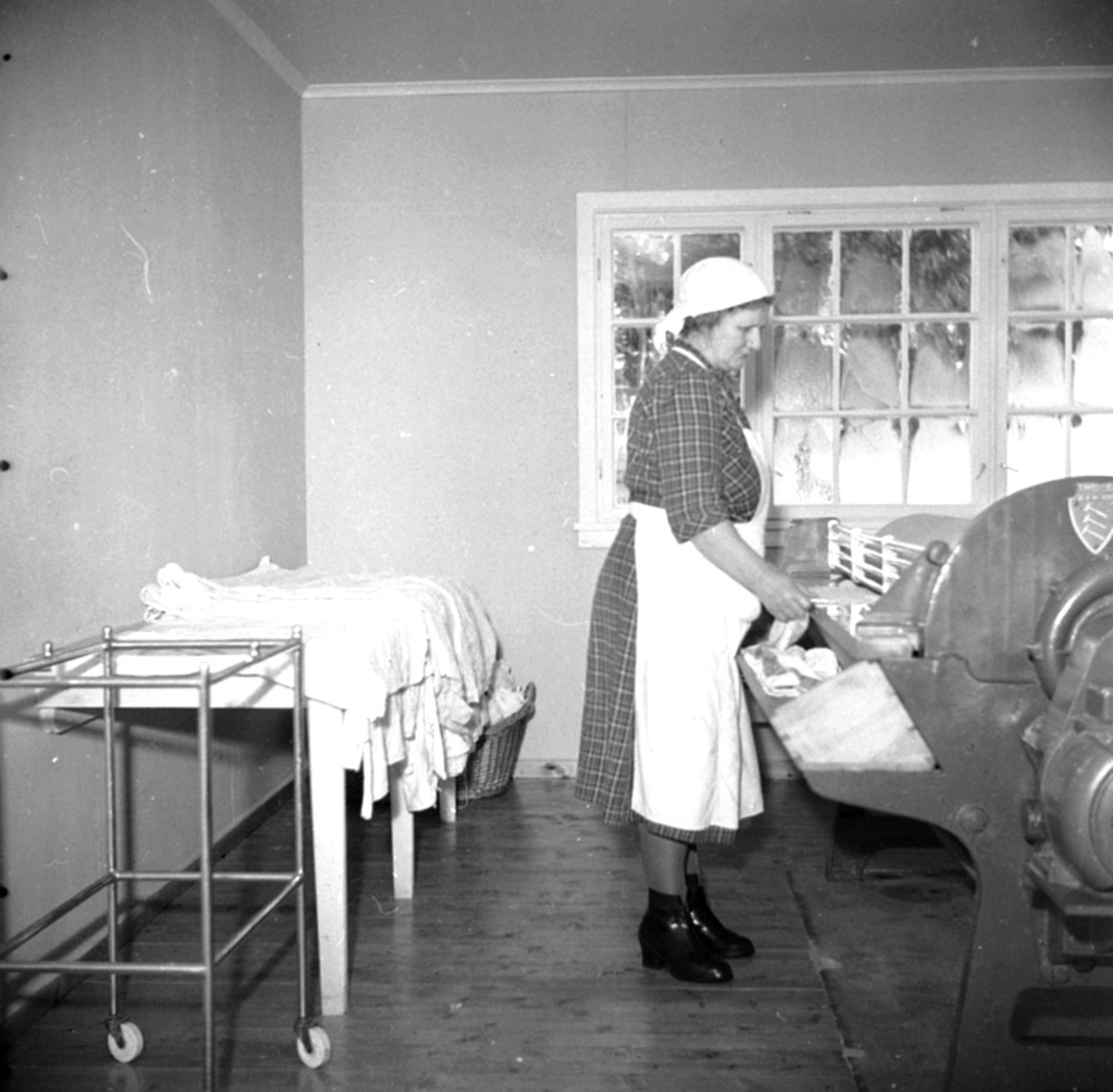 Anno Domkirkeodden, INTERIØR: STANGE SYKEHUS, VASKEROM, DAME MED FORKLE OG TØRKLE