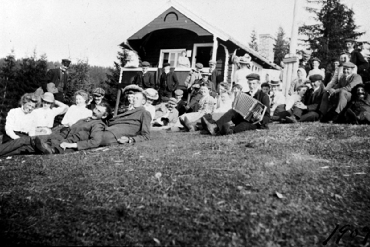 Anno Domkirkeodden, VENSVANGEN I STANGE ALMENNING, STOR GRUPPE UKJENTE UTENFOR HYTTE, 1909