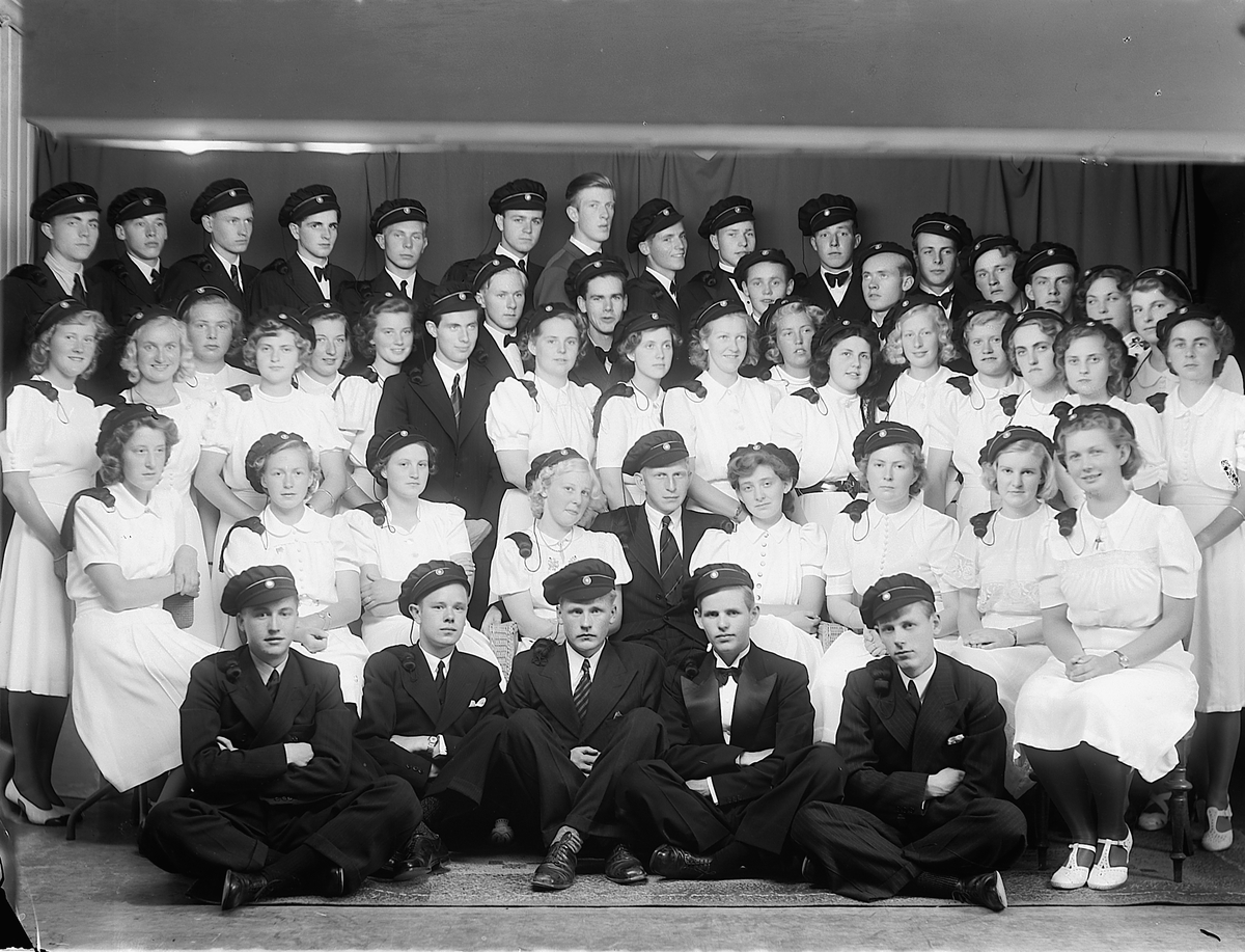 Christian Grundseth, HAMAR KATEDRALSKOLE. STUDENTER. GRUPPE. KVINNER OG MENN. Gunnar Eriksen (1921-2009) stående bakerst i midten uten studentlue. Vitnemålet fra artium på reallinjen ble underskrevet 29. juni. 1940 av Einar Steen. Det var på grunnlag av standpunktkarakter. Det ble ingen eksamen dette året som følge av …