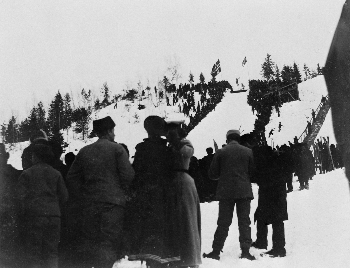 Johan Albert Steen, GRESSBYBAKKEN, FRAMBAKKEN, BRUMUNDDAL, HOPPRENN, PUBLIKUM, FLAGG, SKIRENN. 16-2-1902. Se ”Brumunddalsboka”, utgitt av Hedmarksmuseet 1986 foto nr. 354. Se "Fra bygd til by" Historien om Brumunddal skrevet av Thor Gotaas 2011. s. 131.