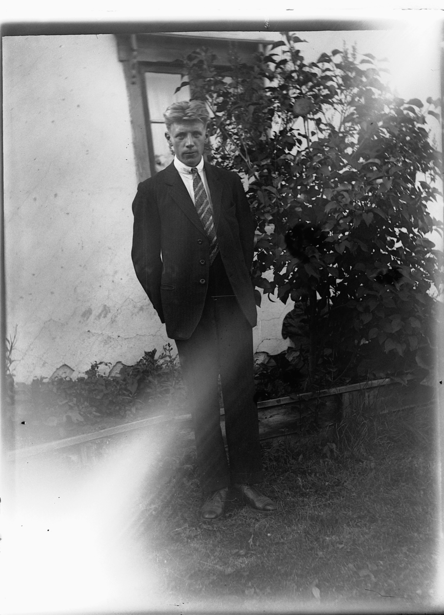 Ole M Martinsen, Ukjent mann foran et hus og blomsterbedd.