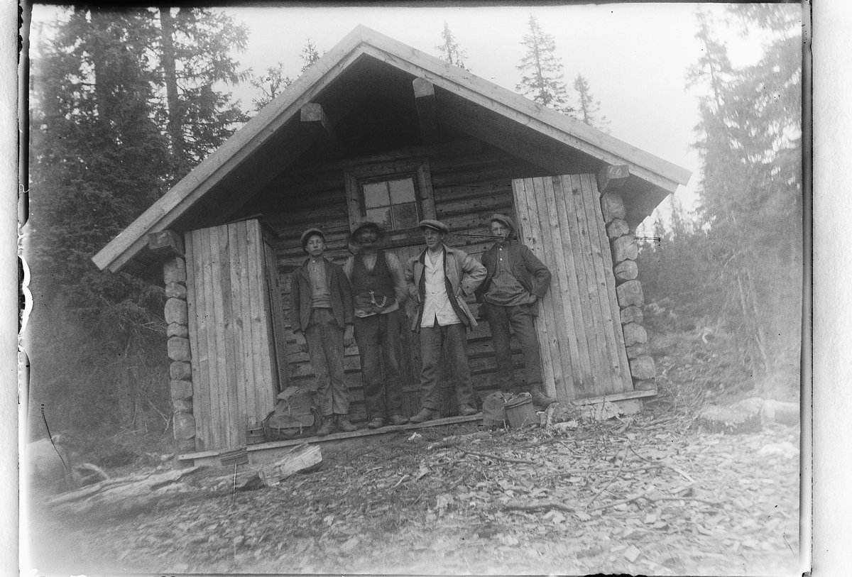 Ole M Martinsen, Eksteriør, skog. Fire ukjente menn foran ei hytte.