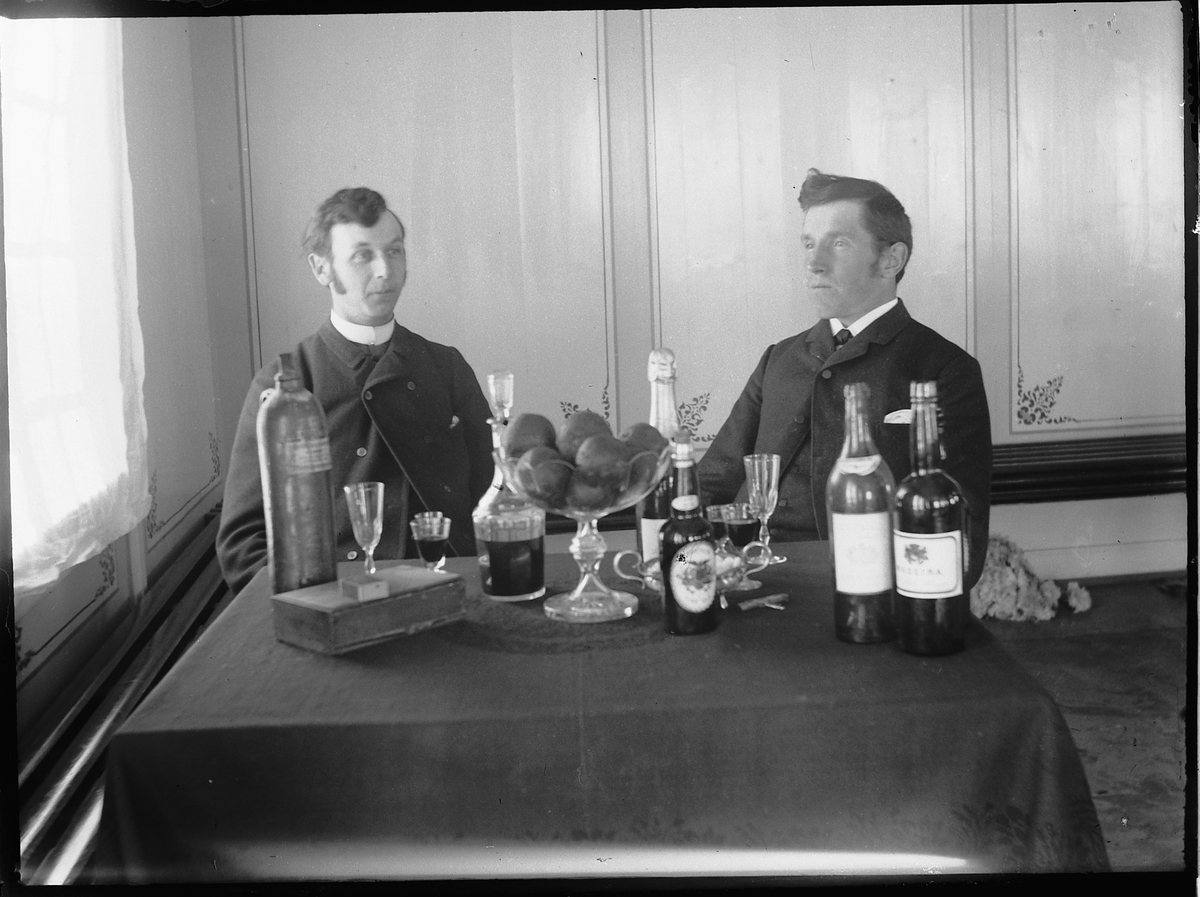 Ole Hansen Løken, F. V. OVRETTSSAKFØRER ALF ULVEN OG OLE LØKEN, FLASKER, GLASS, ALKOHOL, FRUKT PÅ BORDET.
