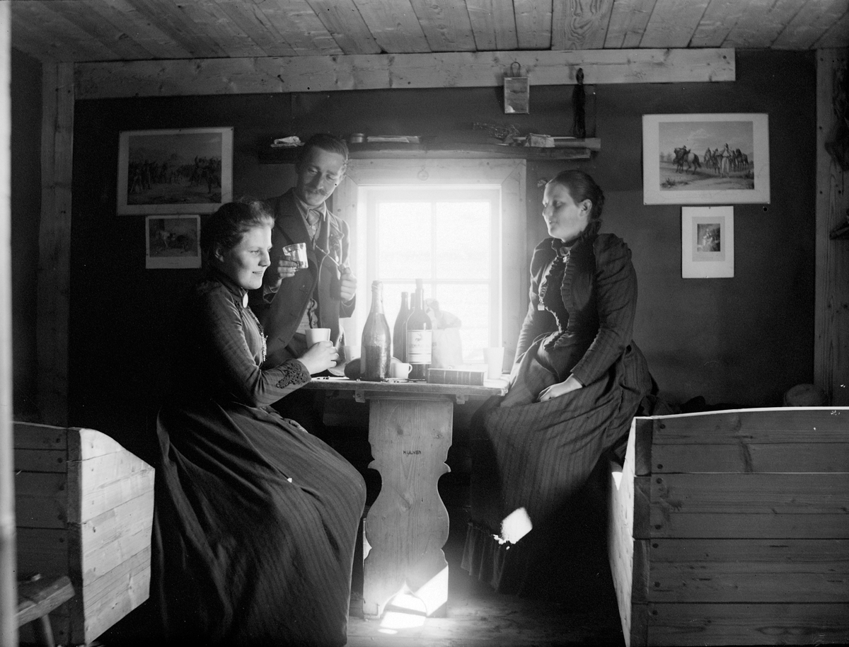 Ole Hansen Løken, Seterhus, interiør, Gammelskolla, unna Løken Østre, . T.v. Antonette Hersaug, forfatter Severin Lieblein, Mimmi Løkken, senger, bord, flasker,glass.