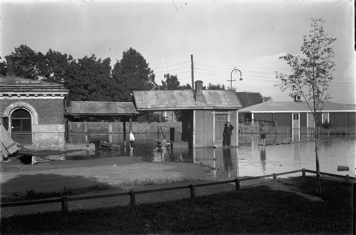 Oscar Løberg, BASARBYGNINGEN i Hamar, FLOM VED KJØTTVEKTA, 1927, BAK I STRANDGATEPARKEN LIGGER AKTUELL KINO. MANNEN MED "FLISTAKET" ER SKOMAKER SVEEN.