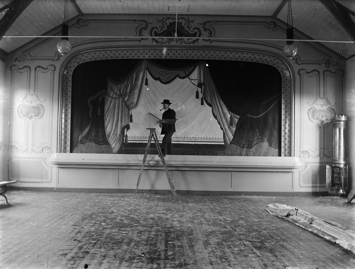 Johs. (Johannes) Johannessen, Teaterscene, Bøndenes hus i Parkgata 31, Hamar. Mann på gardintrapp med pipe i munnen. Arvid Røberg? Dette var Hamar Håndverkerforenings Hus fra 1890 til de flyttet til Østregate 61 i 1923.