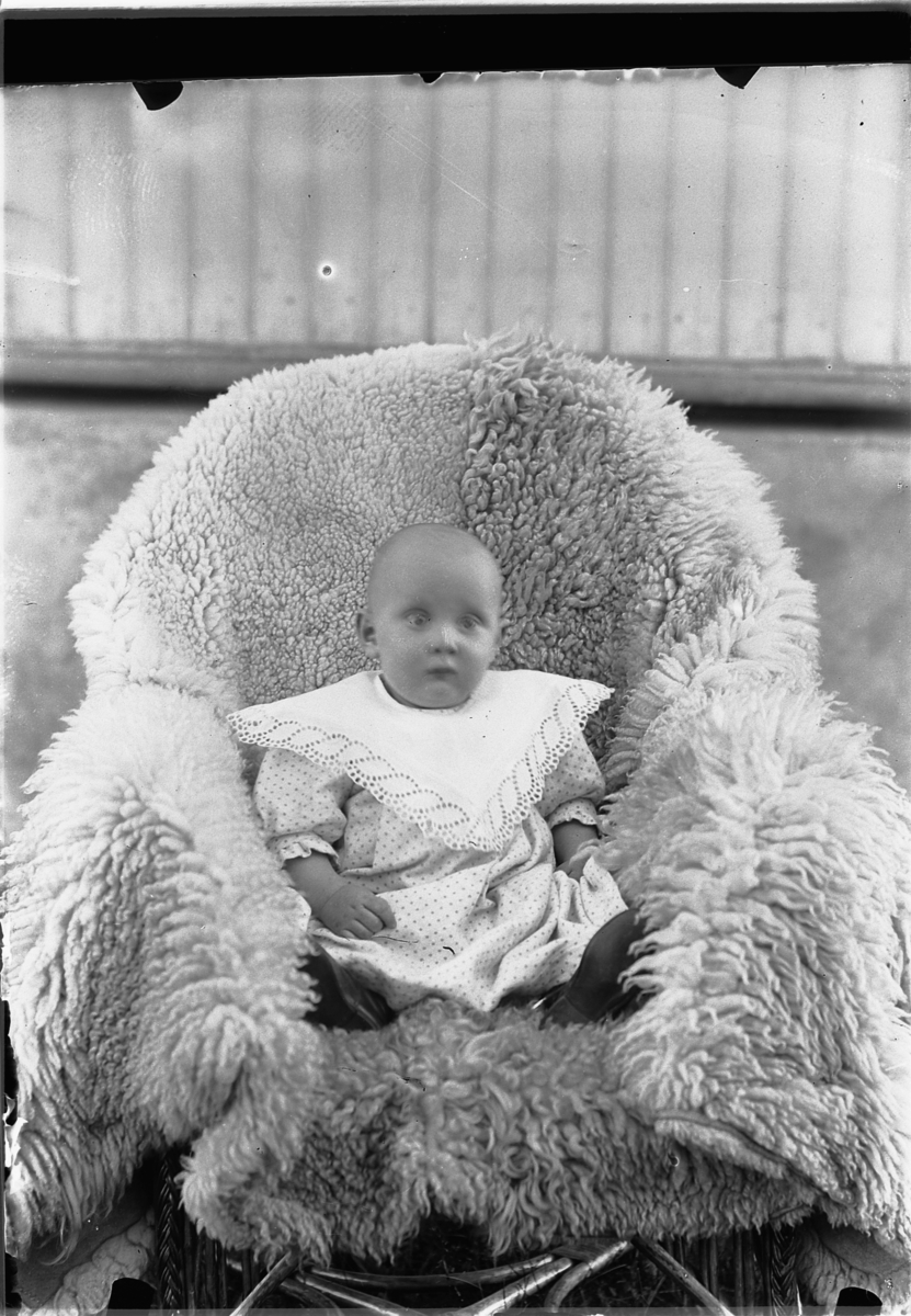Mina Skraastad, En baby på et skinnfell i en stol.