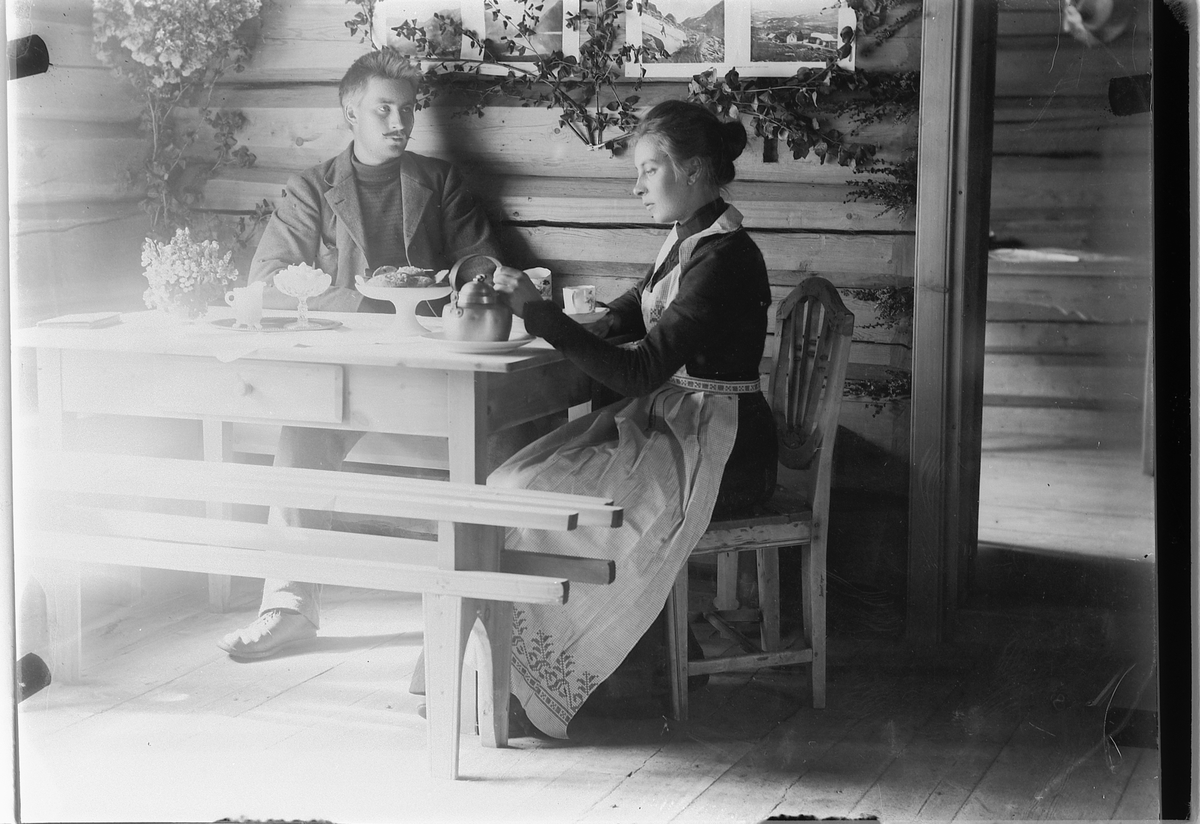 Mina Skraastad, Interiør, stue. Ukjent mann og kvinne drikker kaffe ved et bord.