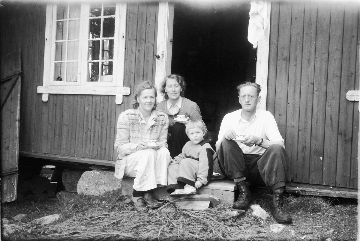 Håkon Prestkværn, Ukjent mann, kvinner og barnpå trappa til hytte.