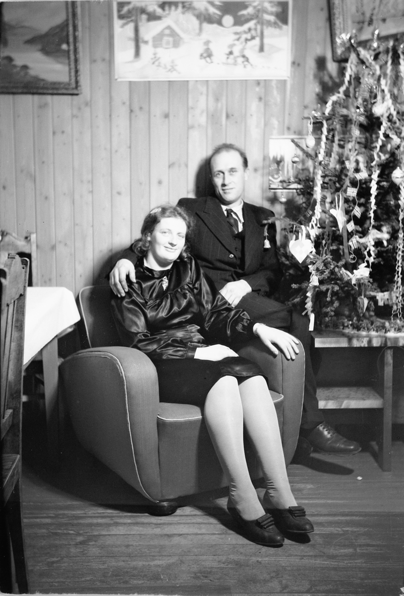 Håkon Prestkværn, Interiør, stue. Sparemøte, Syvertsen. Ukjent kvinne og mann foran juletre.