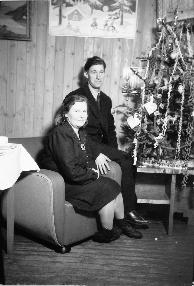 Håkon Prestkværn, Interiør, stue. Sparemøte, Syvertsen. Jenny og Martinus Gjerdingen foran juletre.