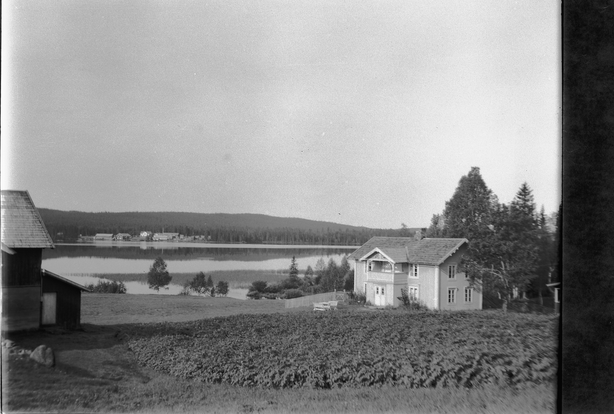 Håkon Prestkværn, Haug gard (Bergundbakken) ved Sør-Mesna. På andre sida av Mesna sees husene på Messensaga. Landskap med hus og sjø.