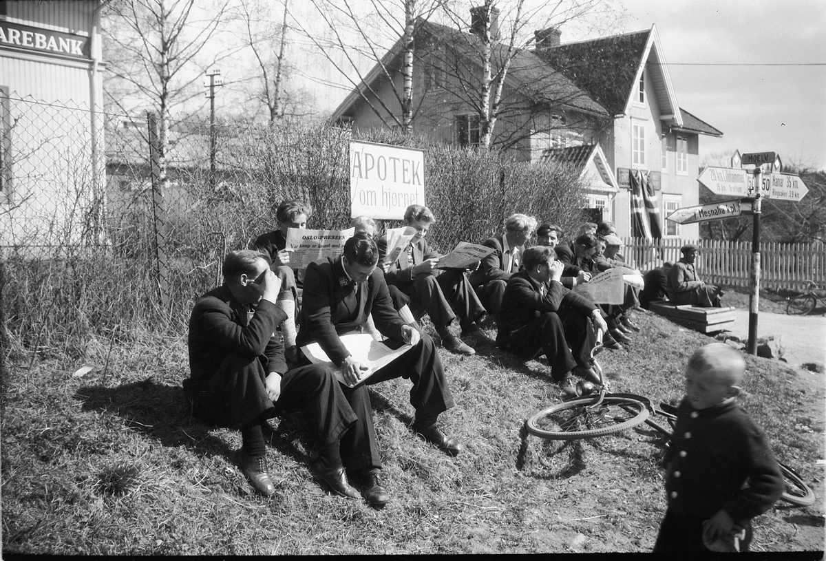 Håkon Prestkværn, Fredsdager etter krigen, mai 1945, Storgata i Moelv, en gruppe kvinner og menn leser aviser.