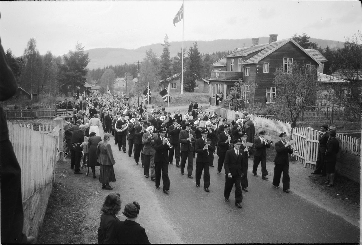 Håkon Prestkværn, Stor gruppe mennesker går i tog med faner og norske flagg. Fremst går musikkorpset. Moelv ved Fønix.