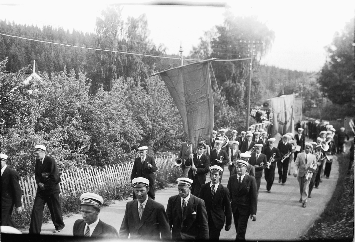 Håkon Prestkværn, Musikkorps marsjerer med fane.