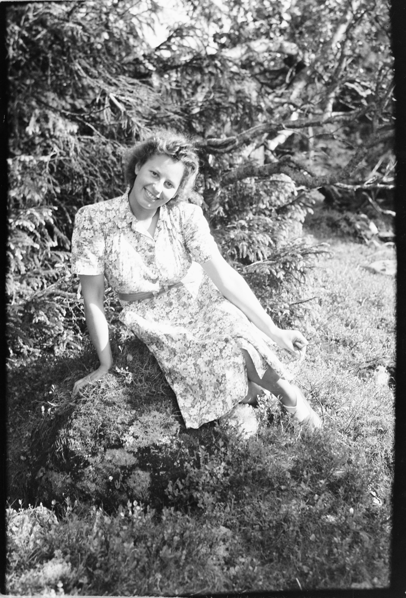 Håkon Prestkværn, Ukjent kvinne i kjole sitter på en stein i skogen.