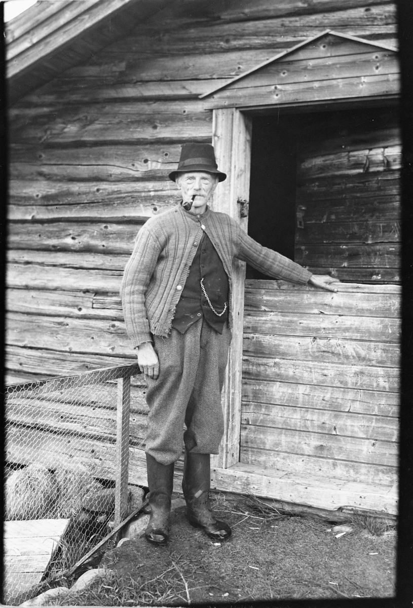 Håkon Prestkværn, Eldre mann med pipe foran dør.