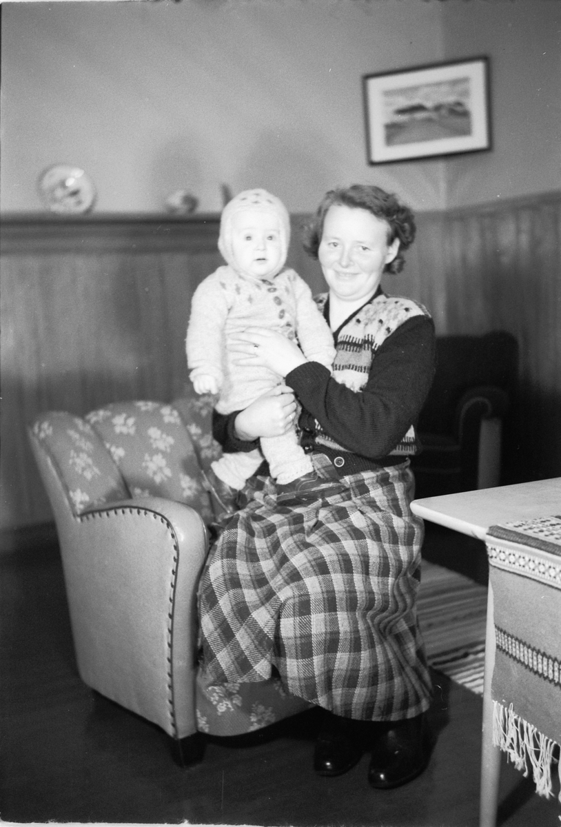 Håkon Prestkværn, Interiør, stue. Ukjent kvinne med en baby på armen.