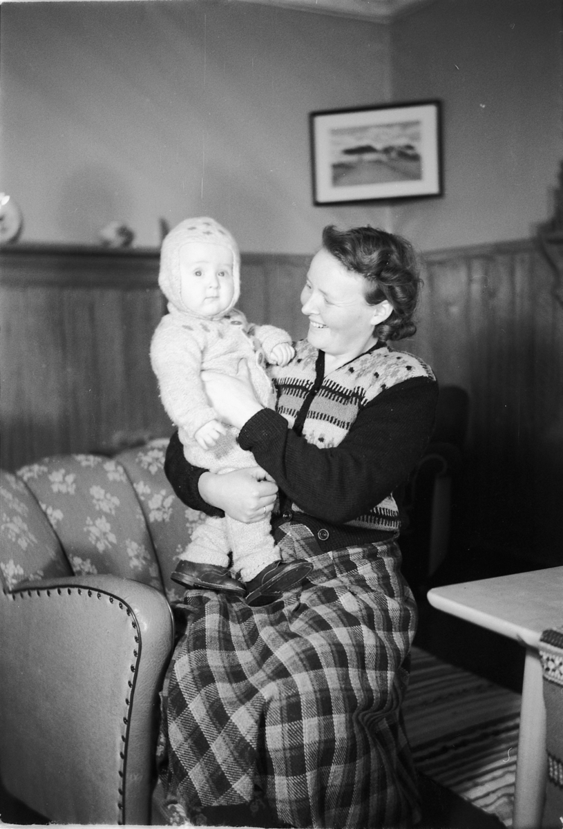 Håkon Prestkværn, Interiør, stue. Ukjent kvinne med en baby på armen.