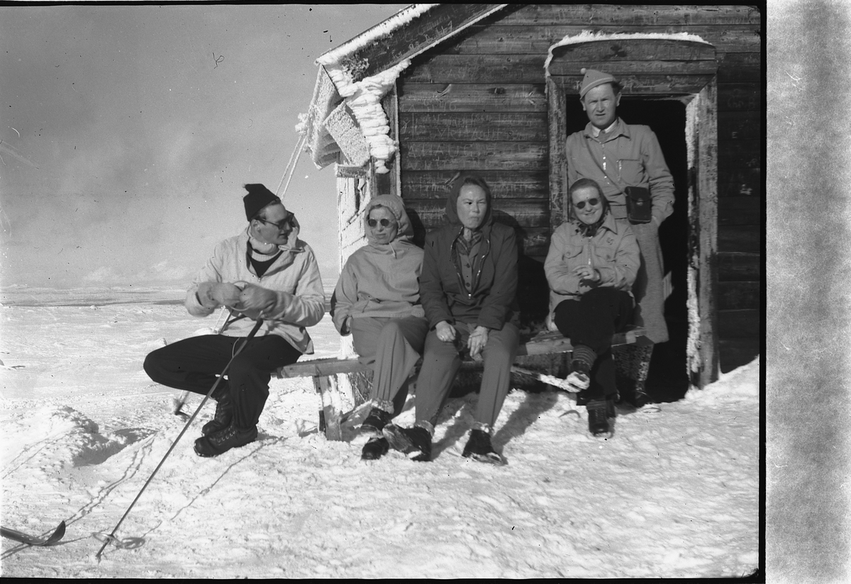 Håkon Prestkværn, Gruppe kvinner og menn i hytteveggen.