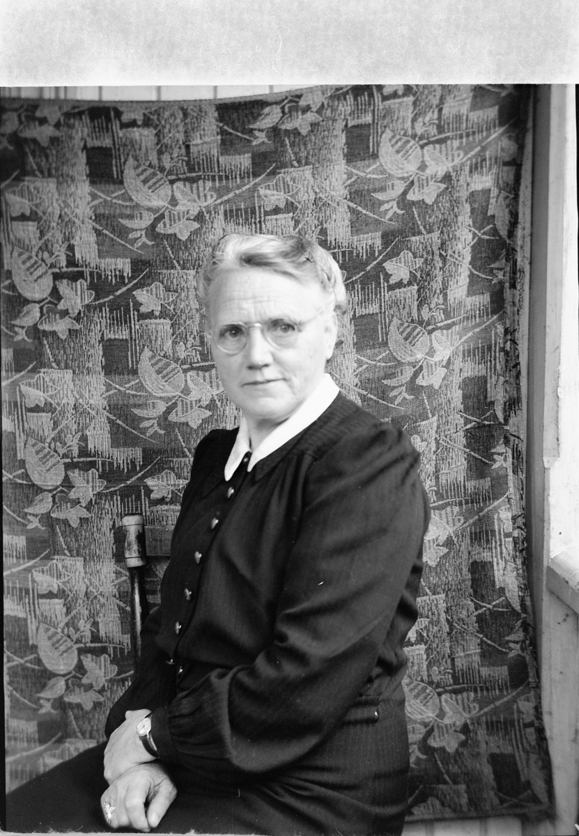 Håkon Prestkværn, Eldre kvinne med briller på en stol.