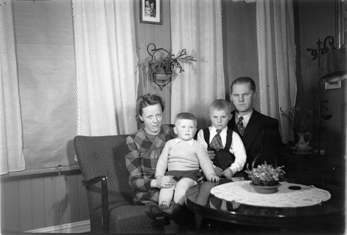 Håkon Prestkværn, Interiør, stue. Familien til Slakter Bjerke. Sittende i sofaen fra venstre Laura f. 1915, Egil? eller Arild? (f. 1946, ) Jan (f. 1942) og Erling Bjerke.