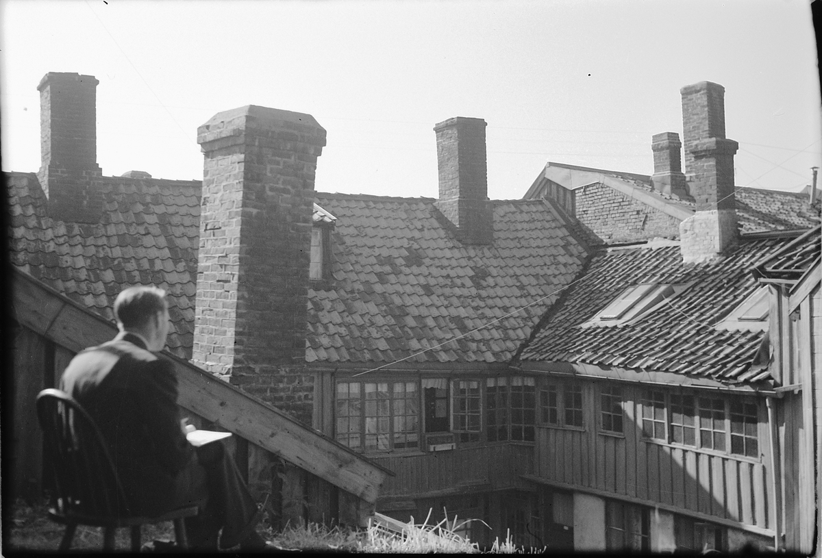 Håkon Prestkværn, Mann, Åsmund Haug, på en stol i en bakgård på øvre Bakklandet 35, Trondheim.