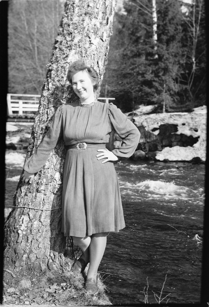 Håkon Prestkværn, Ukjent kvinne står inntil et tre ved ei elv. Fotokonvolutt mrk. "Frknr. Hagen slutten april 1948"