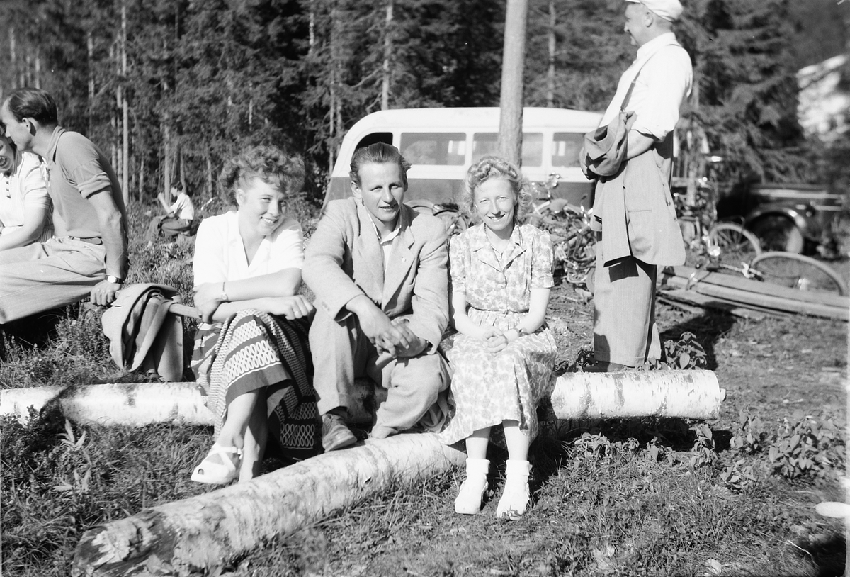 Håkon Prestkværn, To kvinner og en mann sitter på en bjørkestamme.