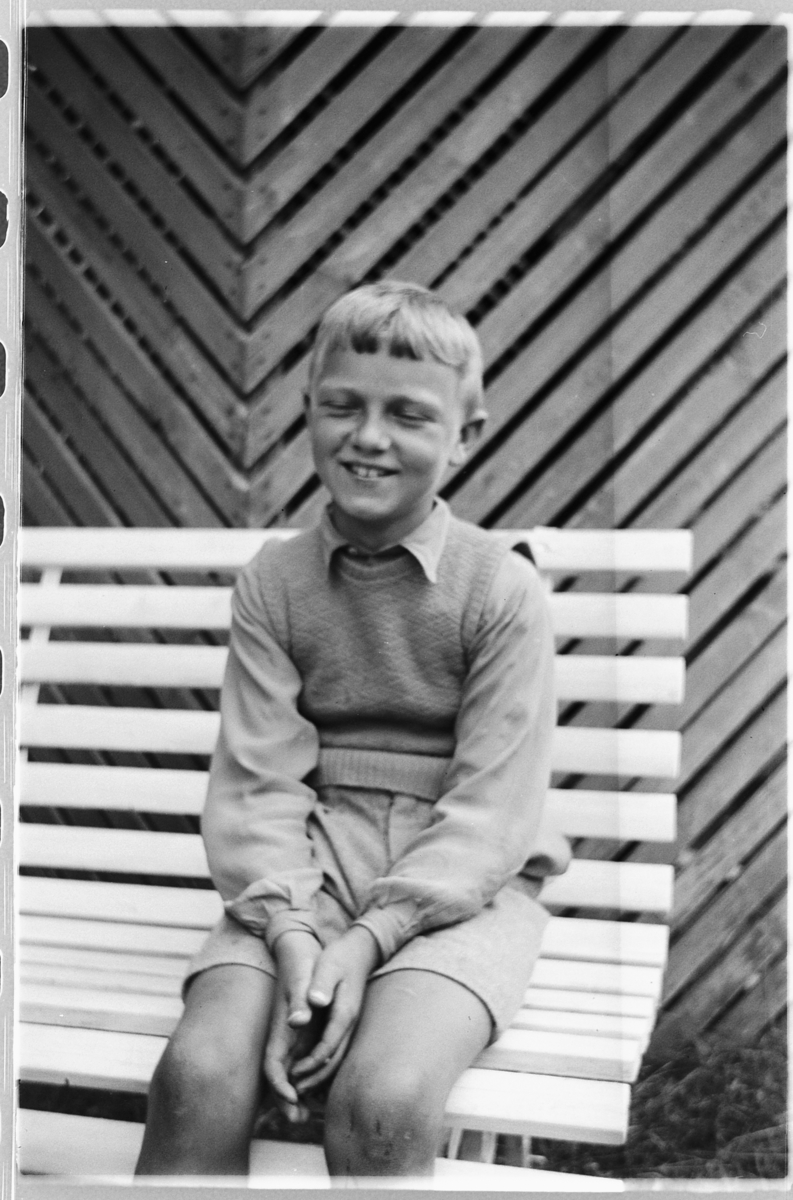Håkon Prestkværn, Eksteriør, hage. En gutt i kortbukse på en benk.