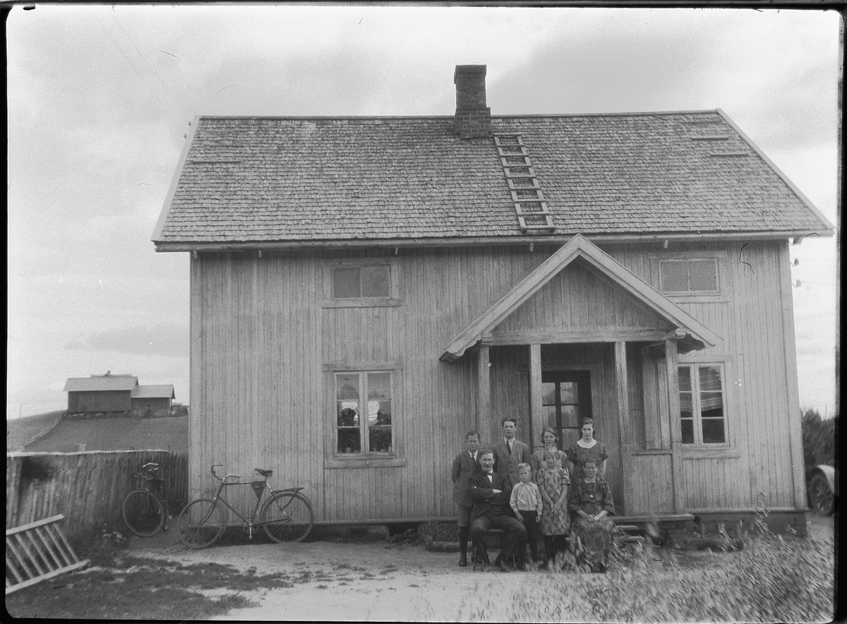 Ole M Martinsen, Ukjent familie ved inngangen til et hus. Sykler inntil husveggen.