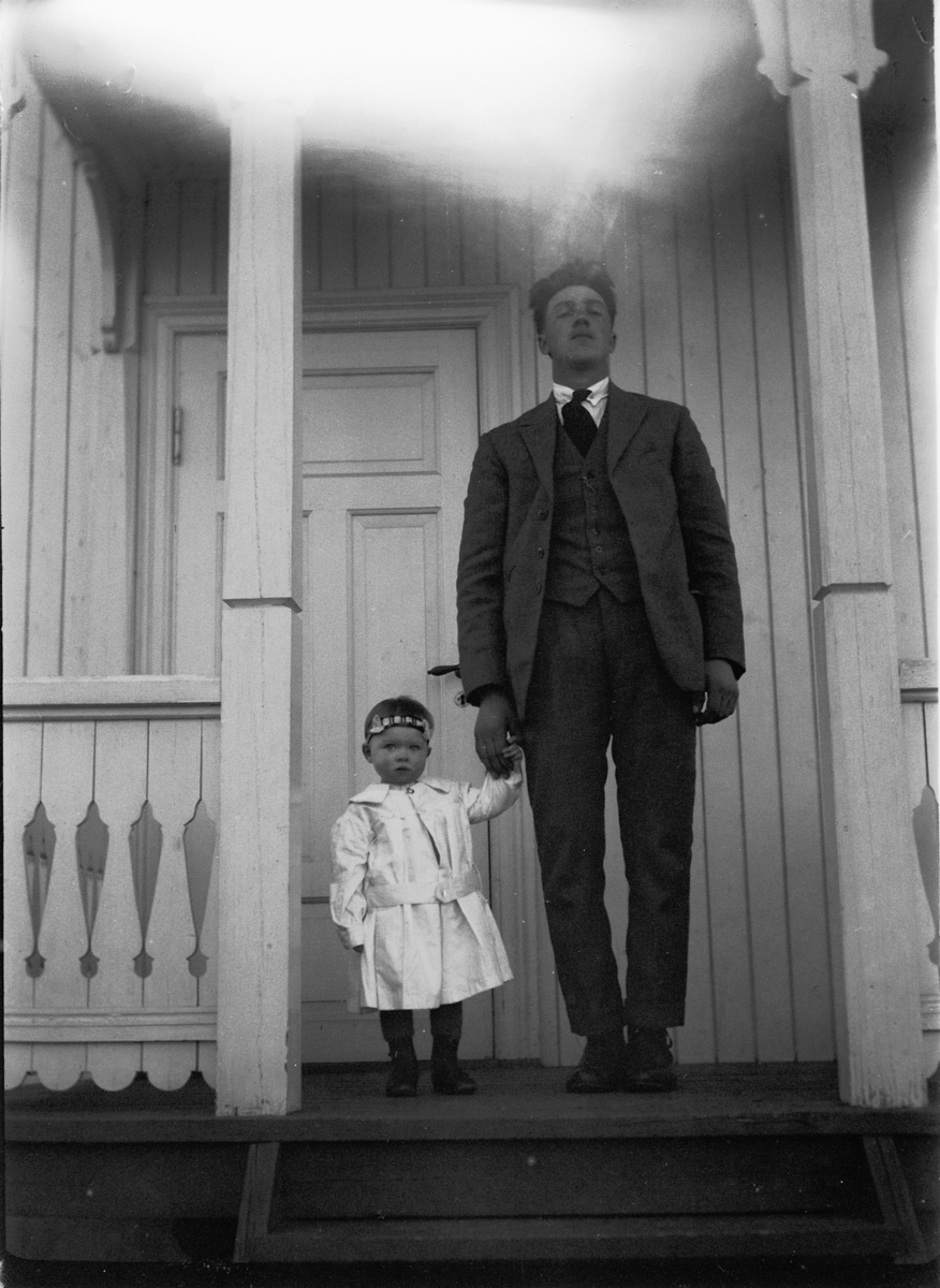 Ole M Martinsen, Ukjent mann og barn holder hverandre i hendene på trammen til et hus.