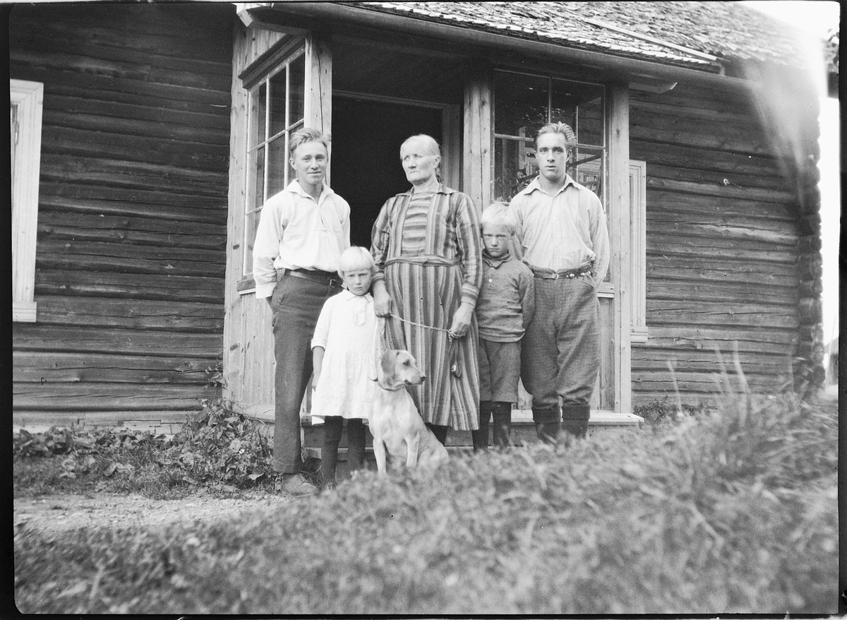 Ole M Martinsen, Ukjent familie med en hund utenfor inngangen til et hus.