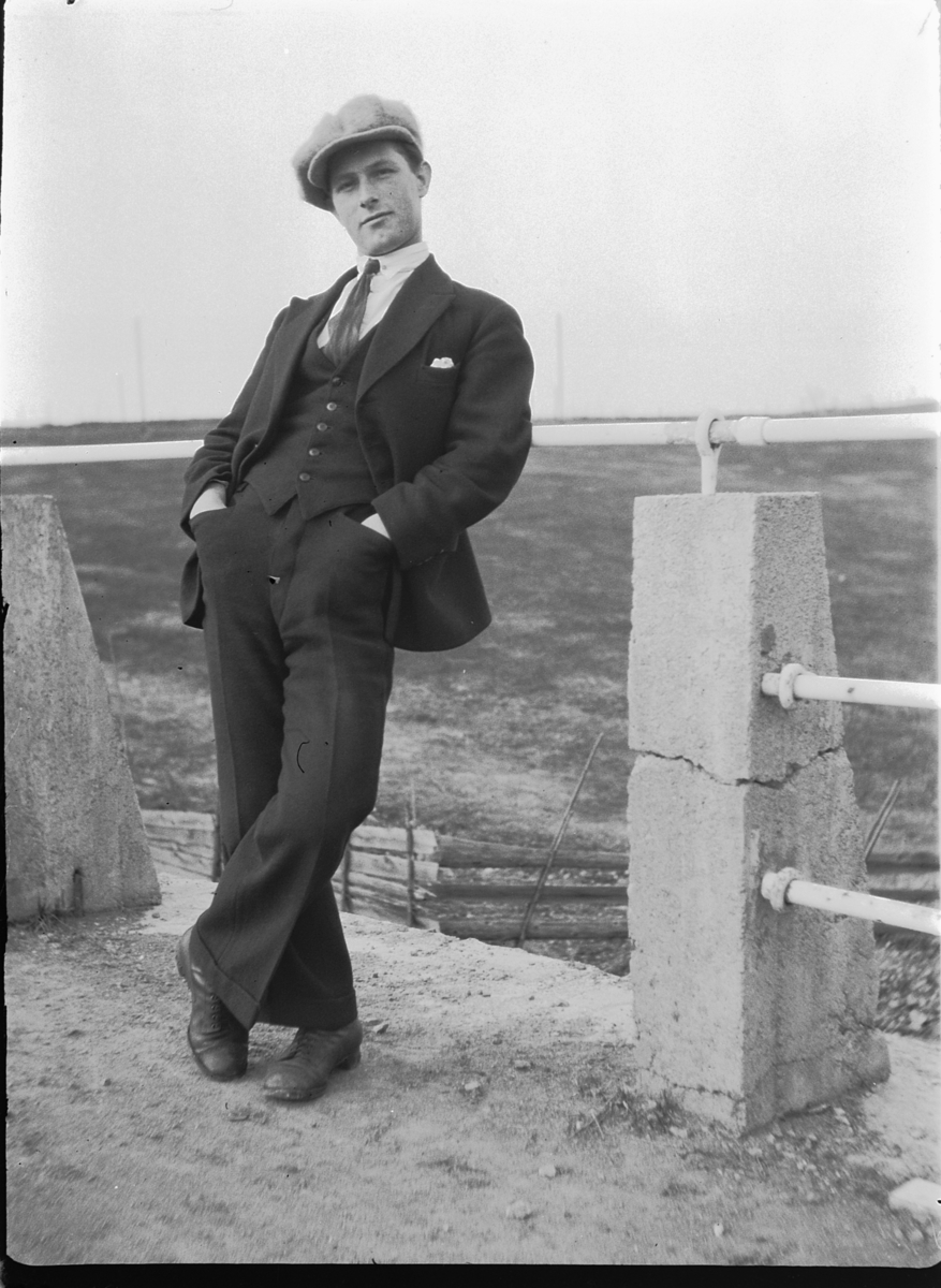 Ole M Martinsen, Ukjent mann med dress og sixpence lener seg til et rekkverk.