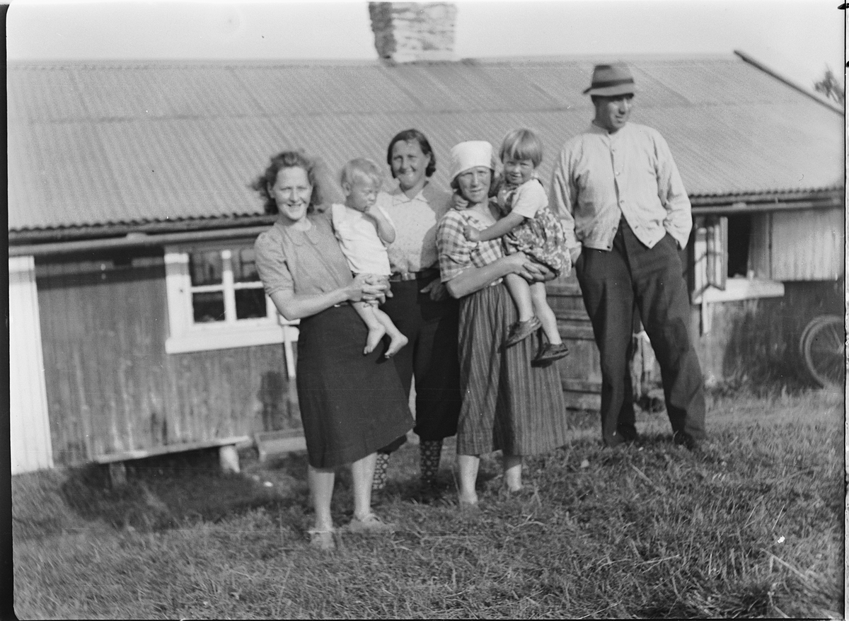 Ole M Martinsen, Ukjent gruppe kvinner, barn og en mann utenfor ei hytte.
